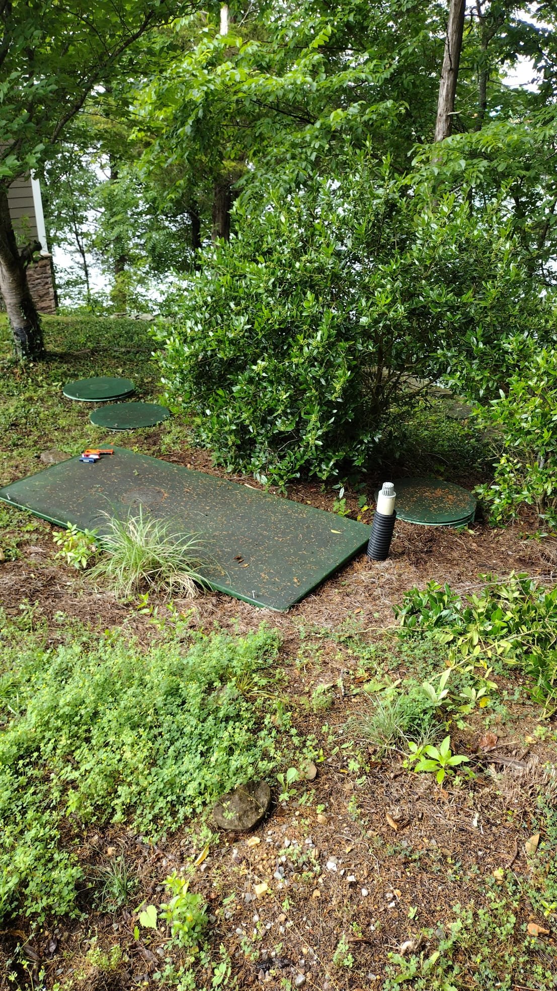 Outdoor septic system setup with green covers and natural surroundings