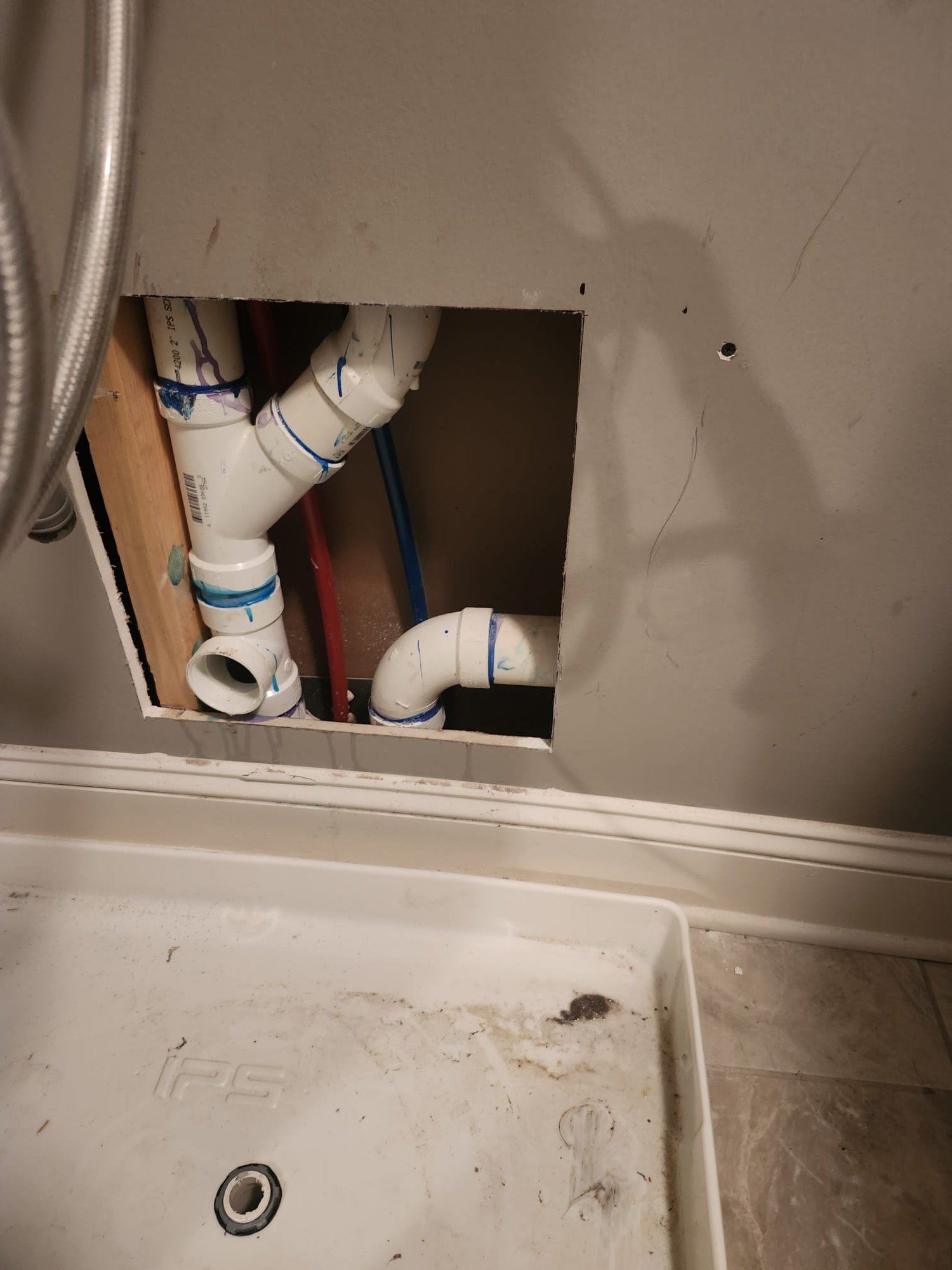 Section of wall with a cut-out revealing new plumbing pipes