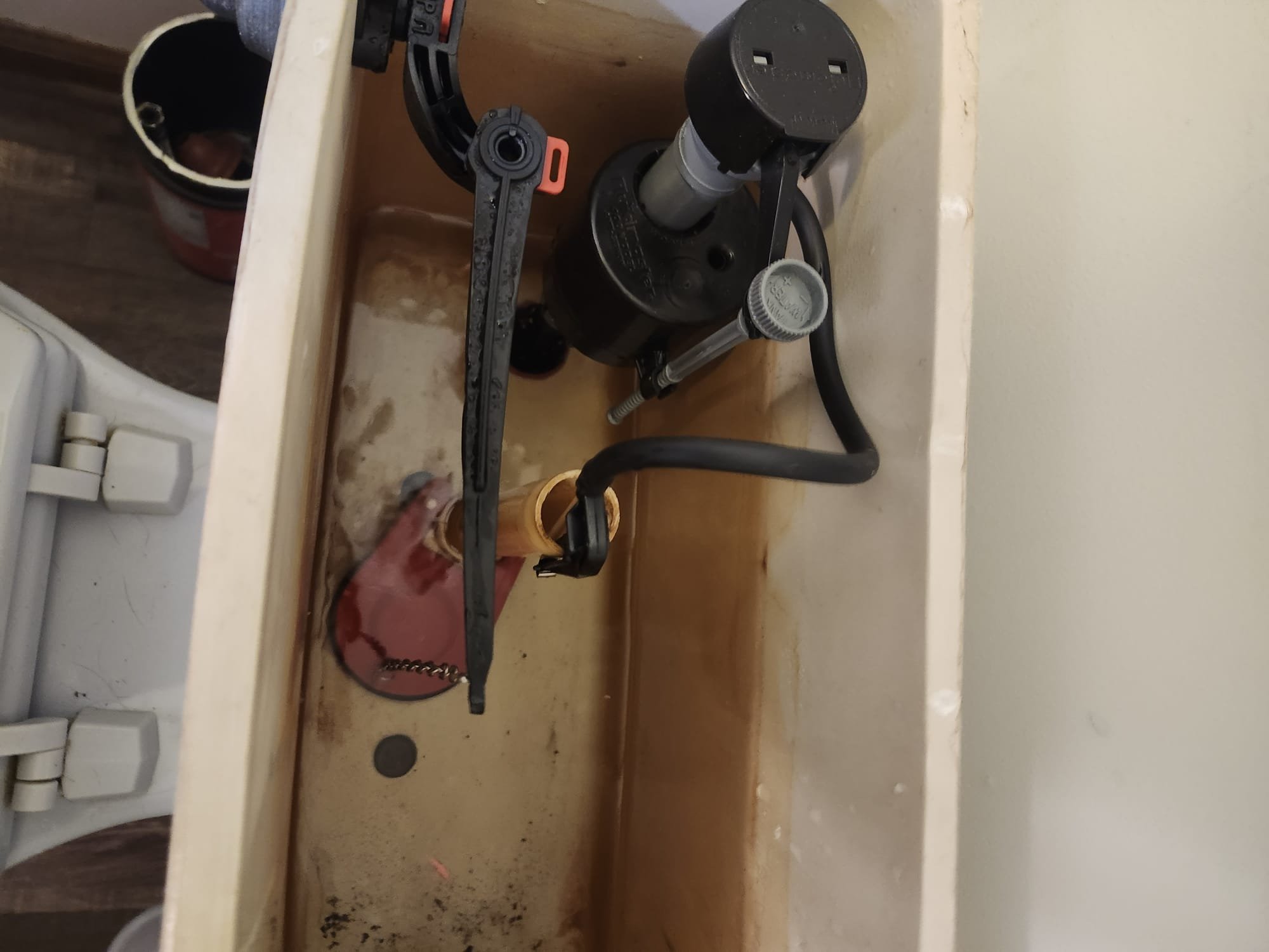 Inside view of a toilet tank after repair, showing a new fill valve and flush lever installation.