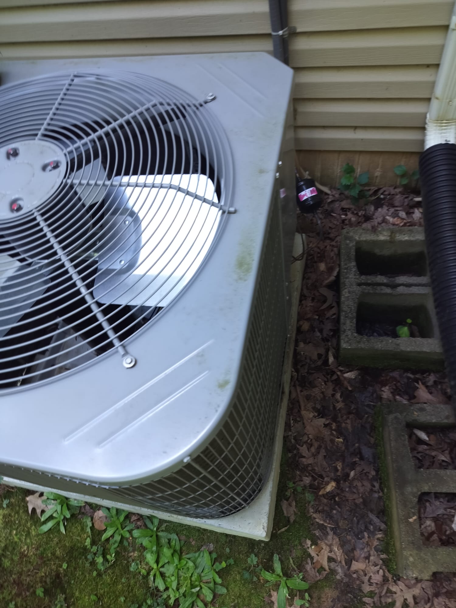 Outdoor HVAC condenser unit with some debris around the base