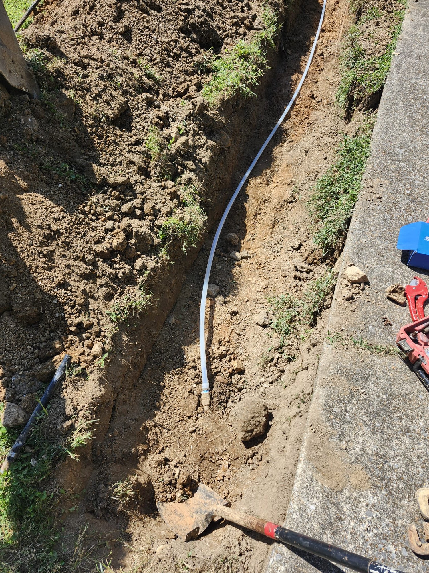 Freshly laid PEX line in trench, ready for backfilling