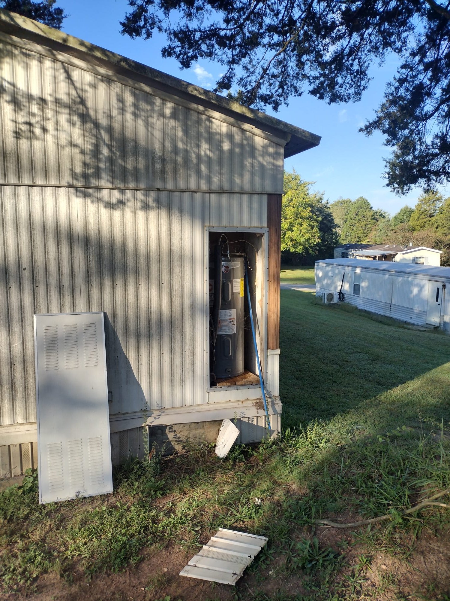 HEP technician inspecting a water heater behind an open access panel