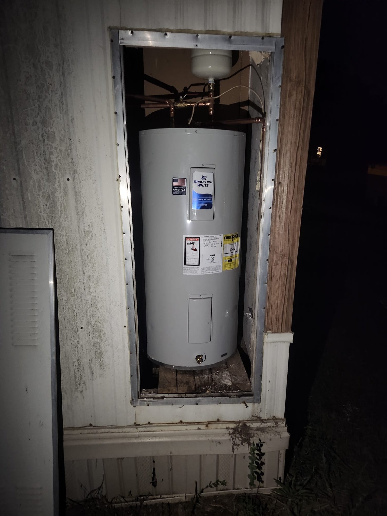 Exterior compartment with a freshly installed water heater and expansion tank