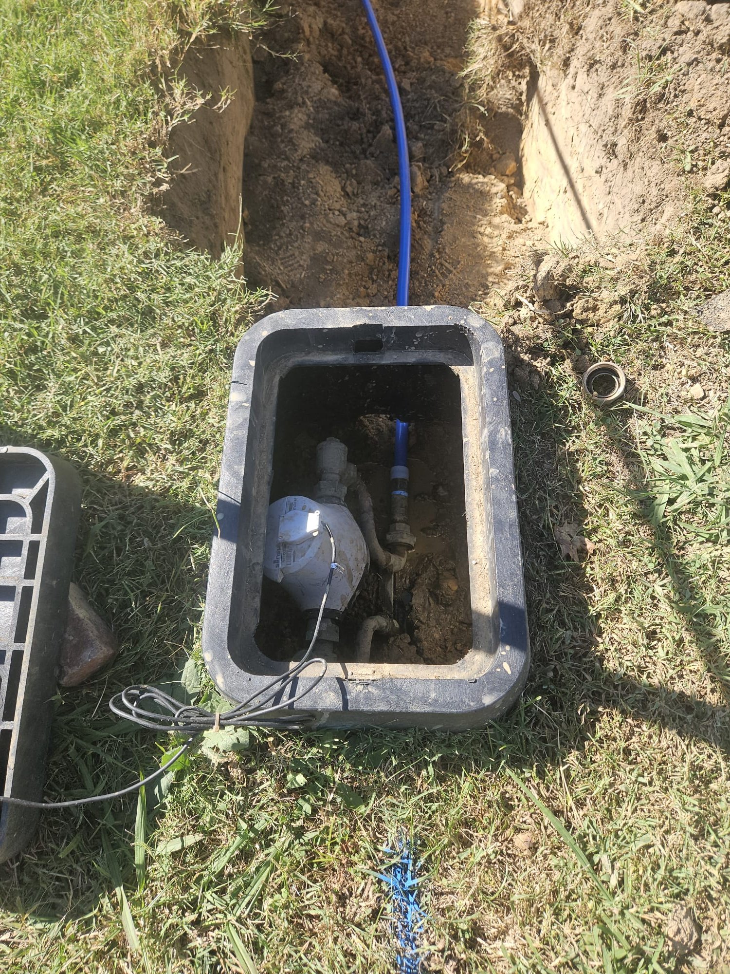 Outdoor water meter box showing new blue service line
