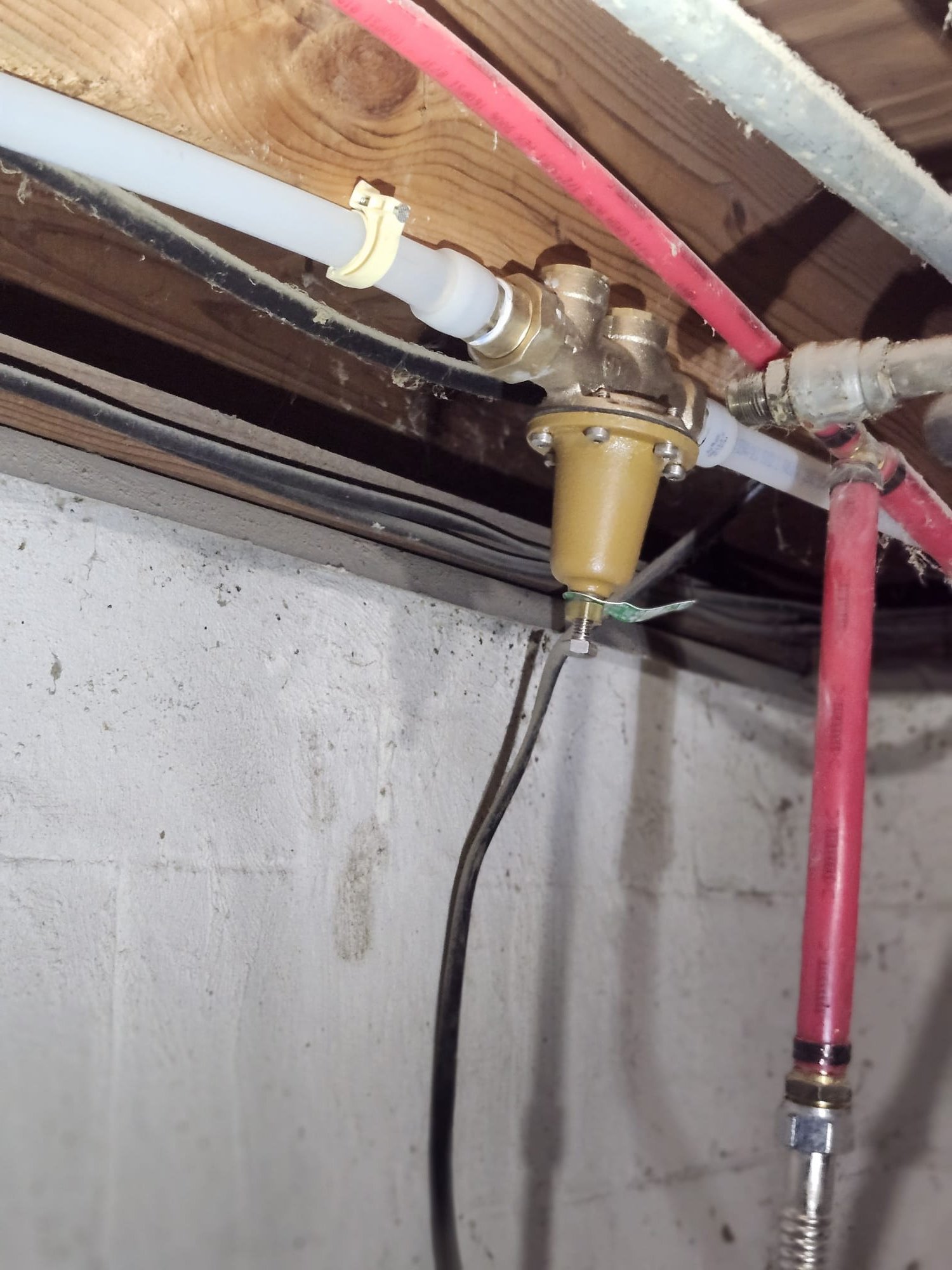 Clean brass fitting and modern piping under joist
