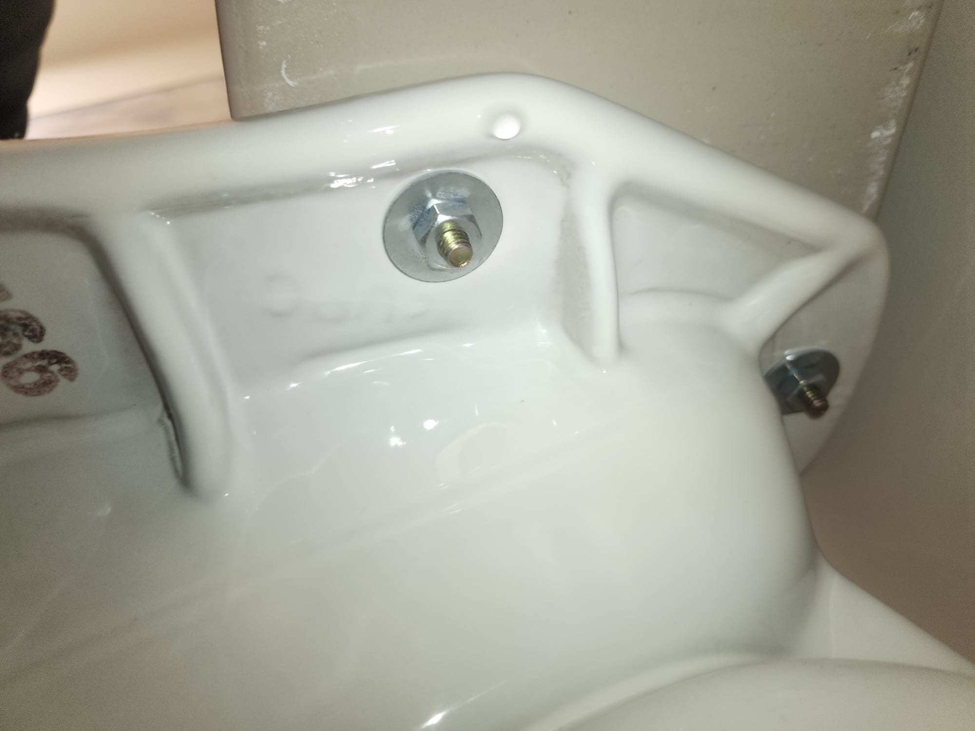 Underside view of a toilet showing new mounting bolts and washers securely fastening the bowl.