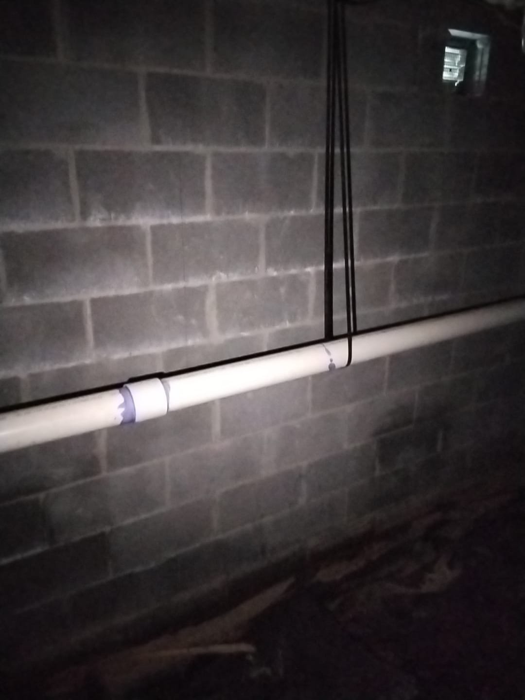 Closeup of new drain line along basement wall