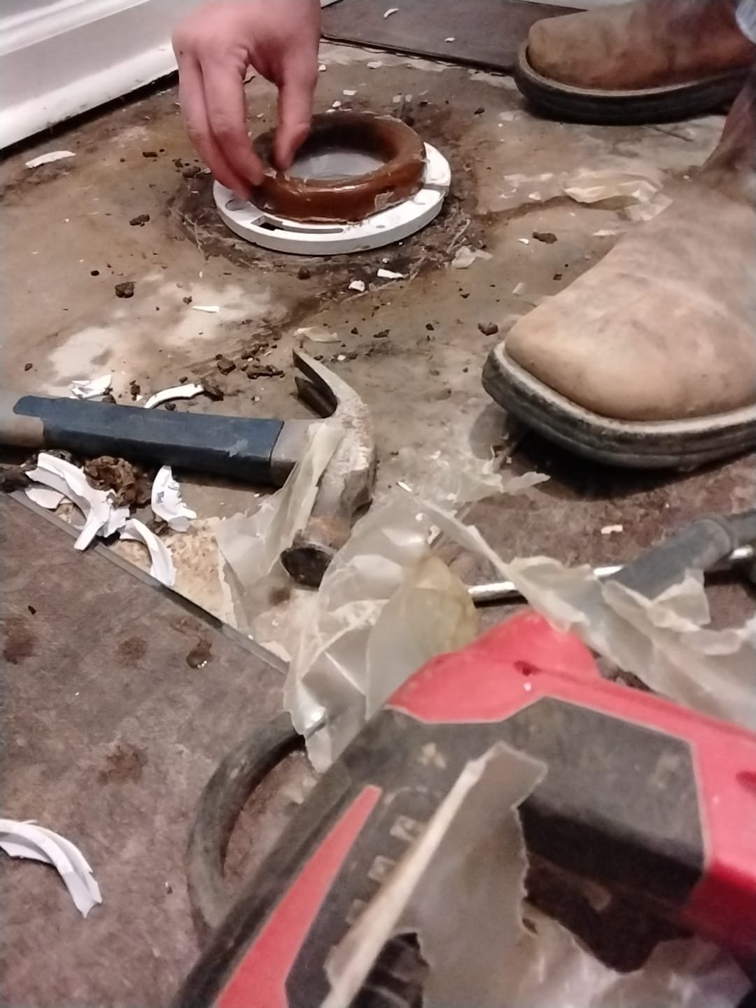 In this image, a technician is placing a new gasket (wax ring) onto the toilet flange to ensure a proper seal between the bowl and the drain.