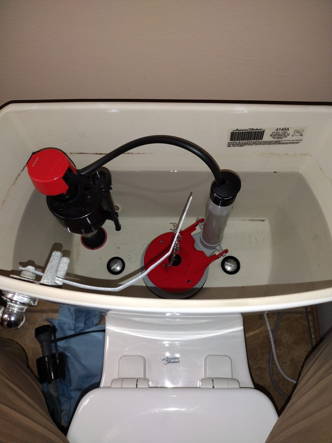 Close-up of newly installed black fill valve and gray flush mechanism