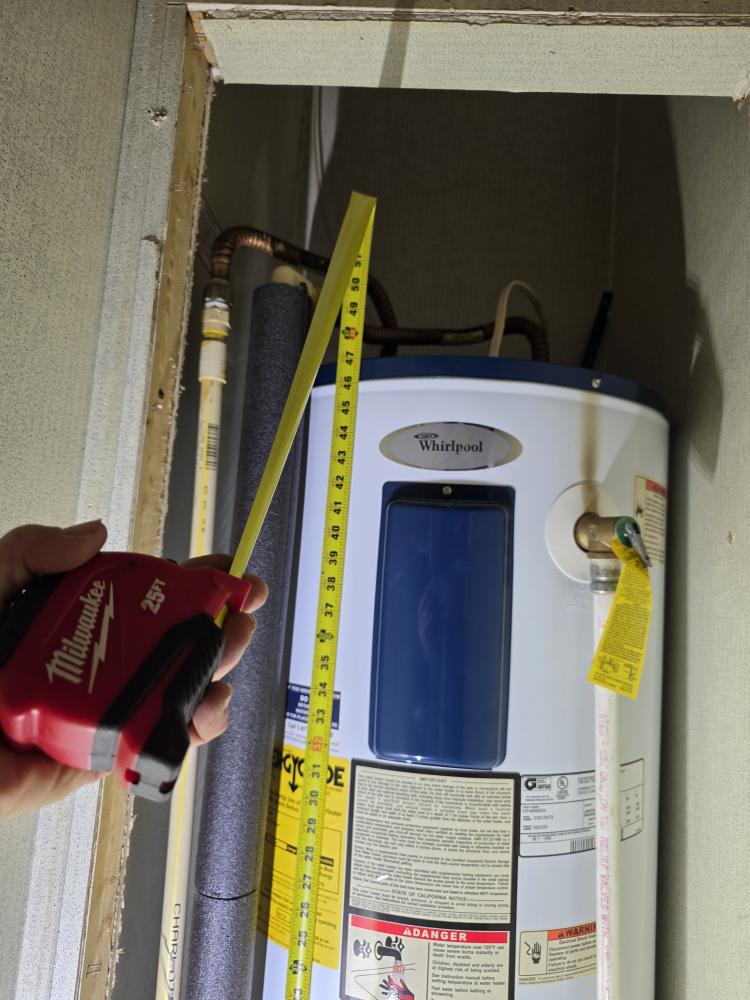 Measuring a newly installed Cleveland-style water heater with a tape measure