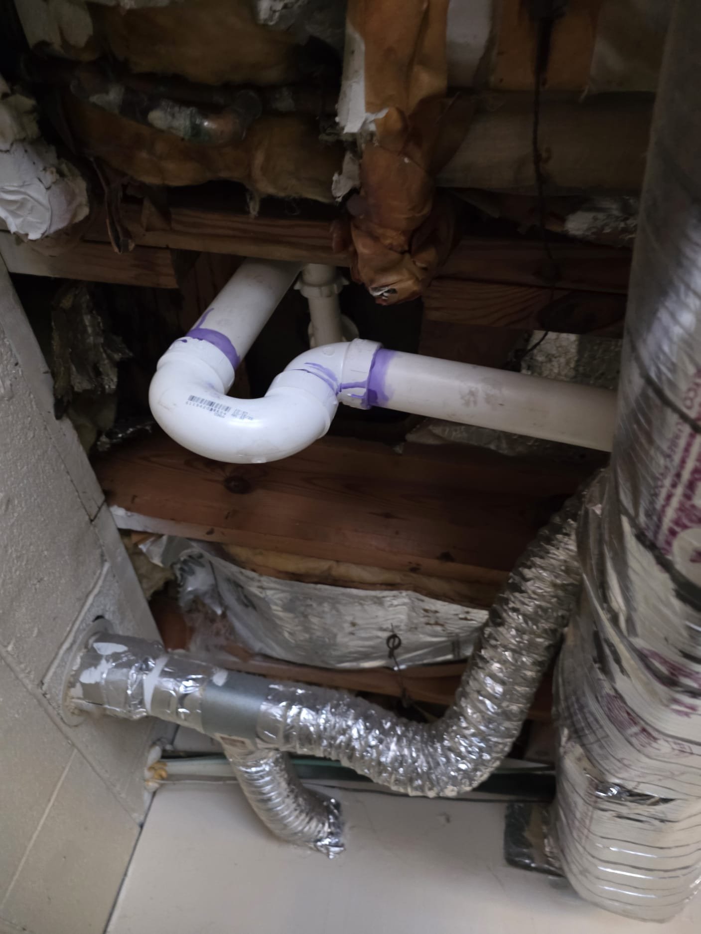 Freshly installed PVC drain assembly with clean primer on the joints