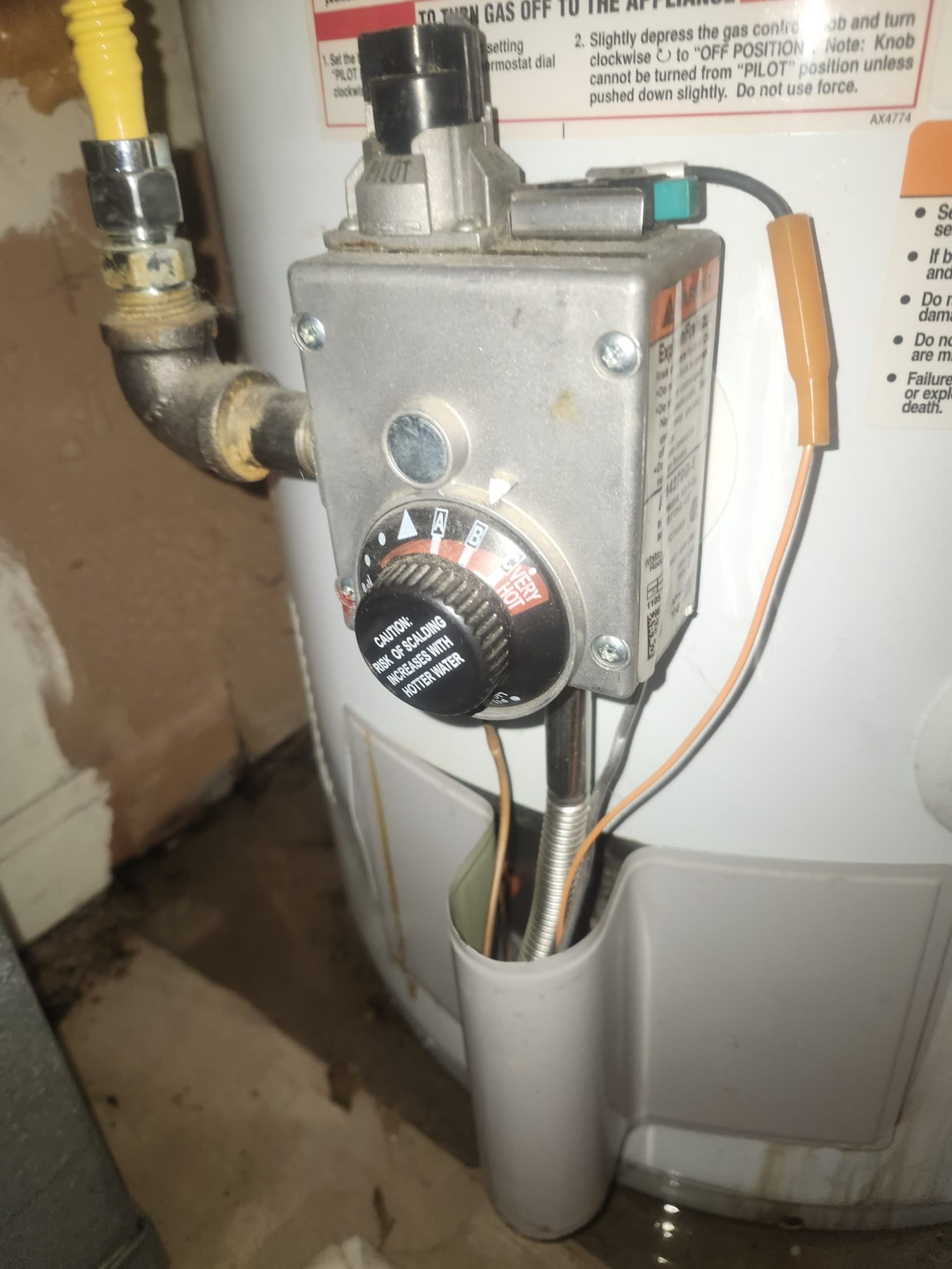 Signs of wear and moisture around an older gas water heater