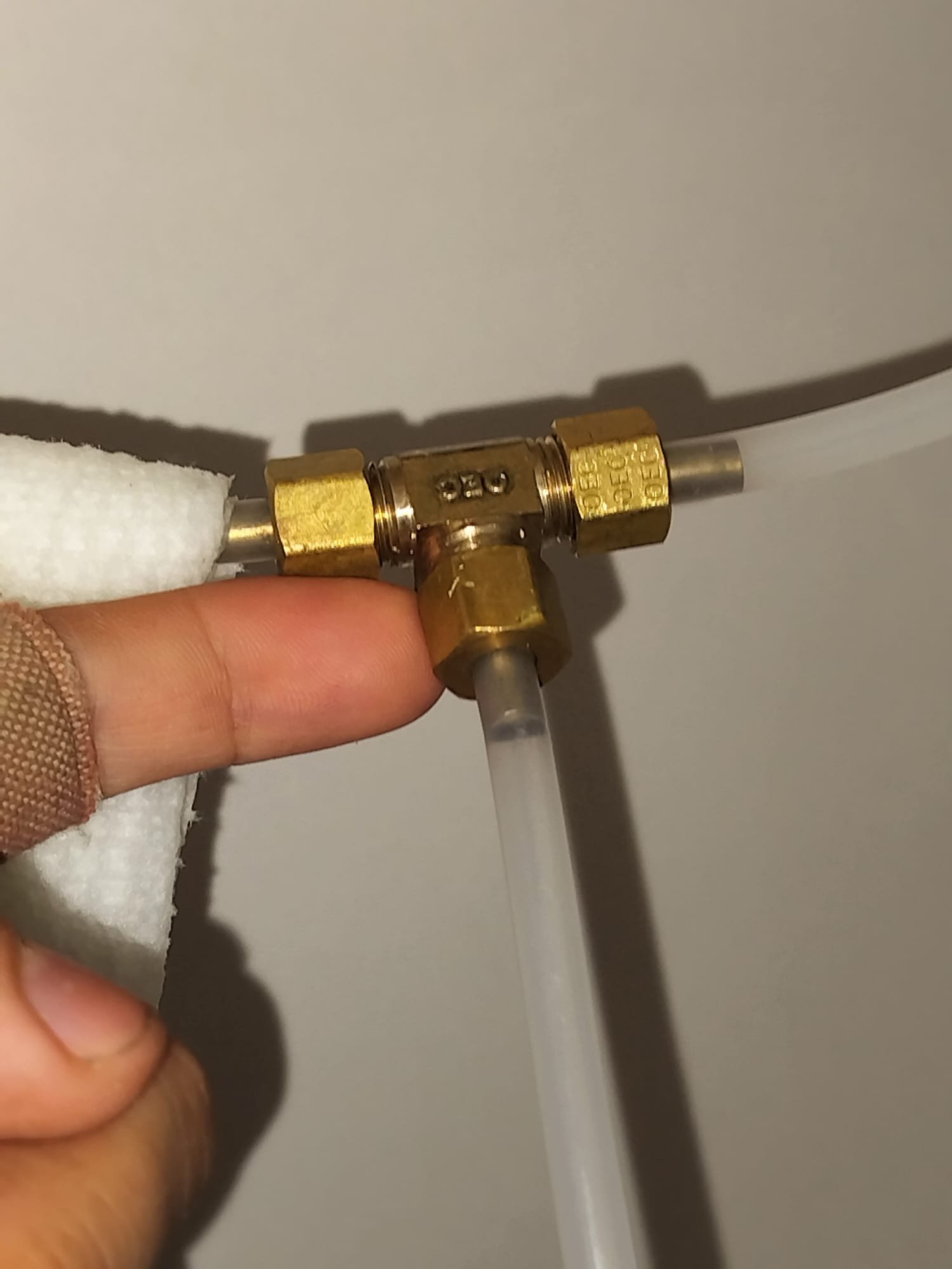 A technician checking a small water-line fitting during service