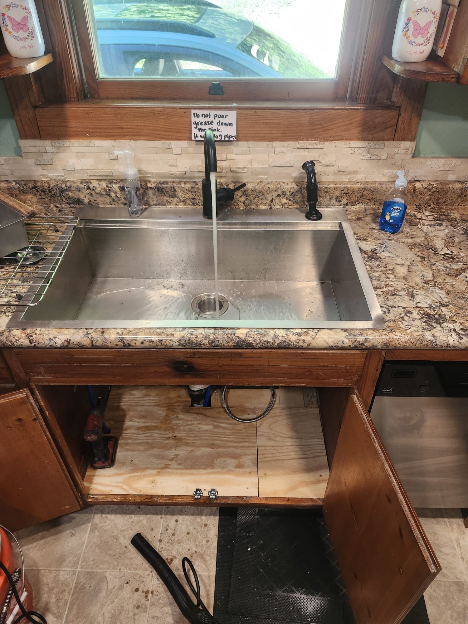 A repaired cabinet floor and sink area after service