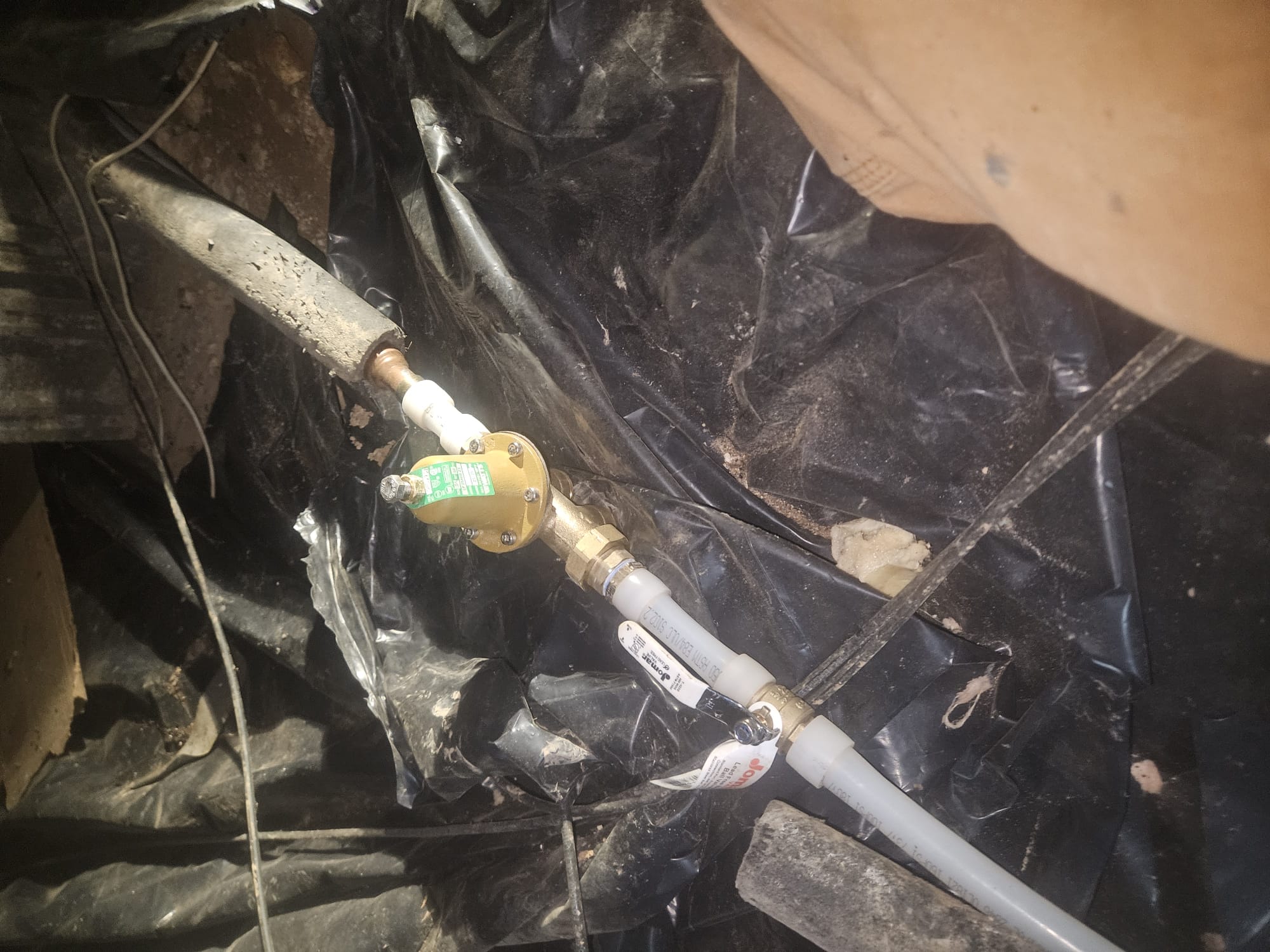 A newly installed brass valve assembly and shutoff valve in a crawl space