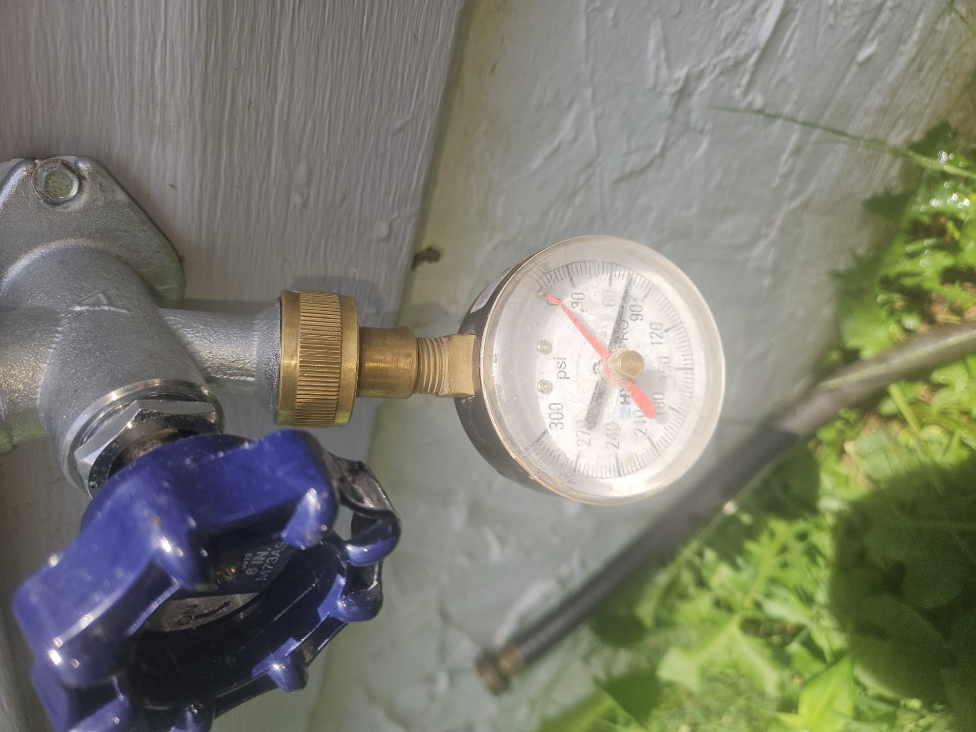 A technician checking water pressure at an outdoor spigot after plumbing service