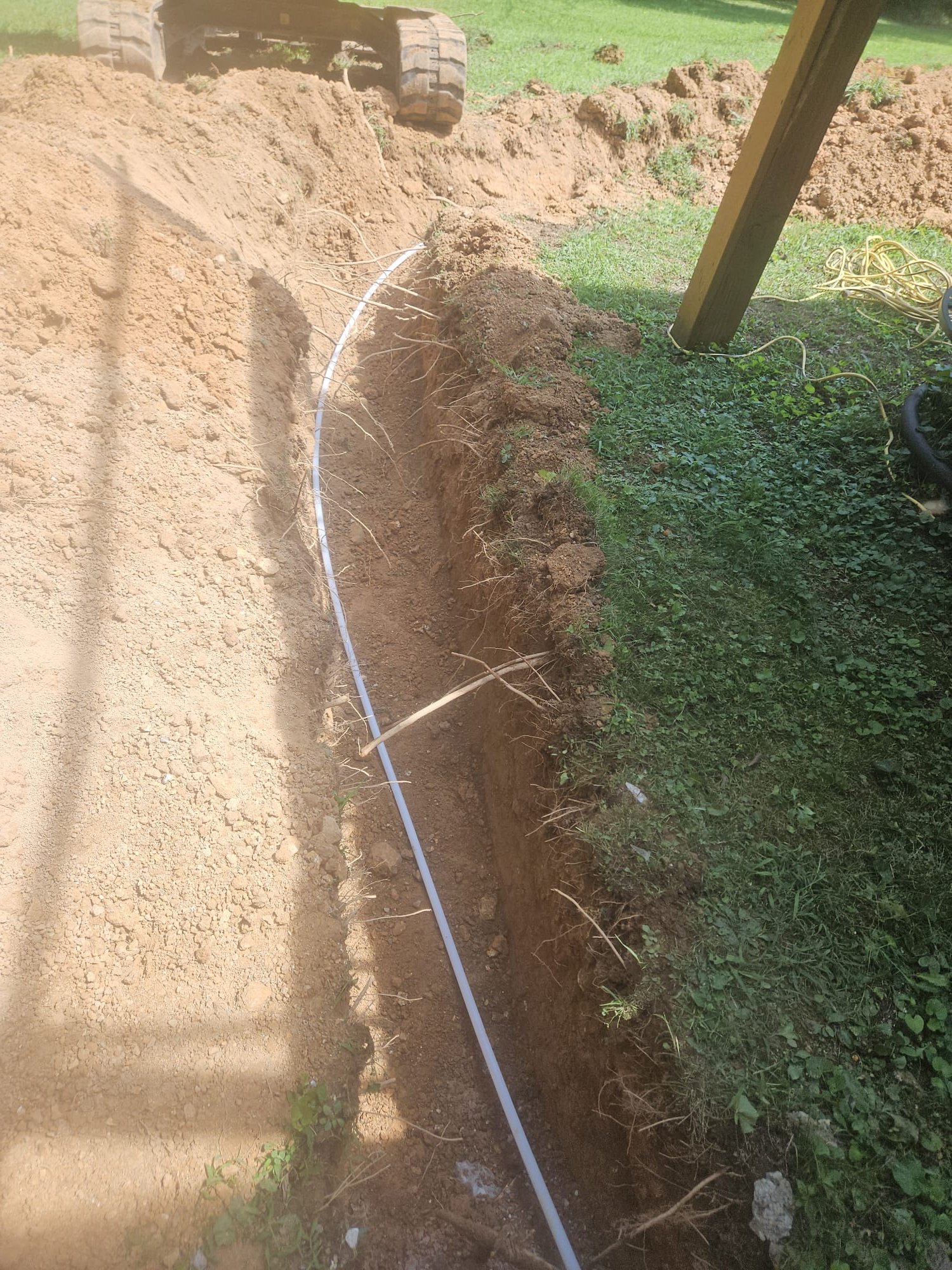 A clean white pipe installed in an open trench during underground plumbing work