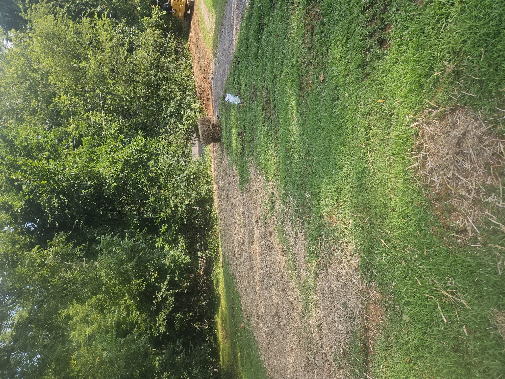 A restored yard area with straw used to help the ground recover after underground plumbing work