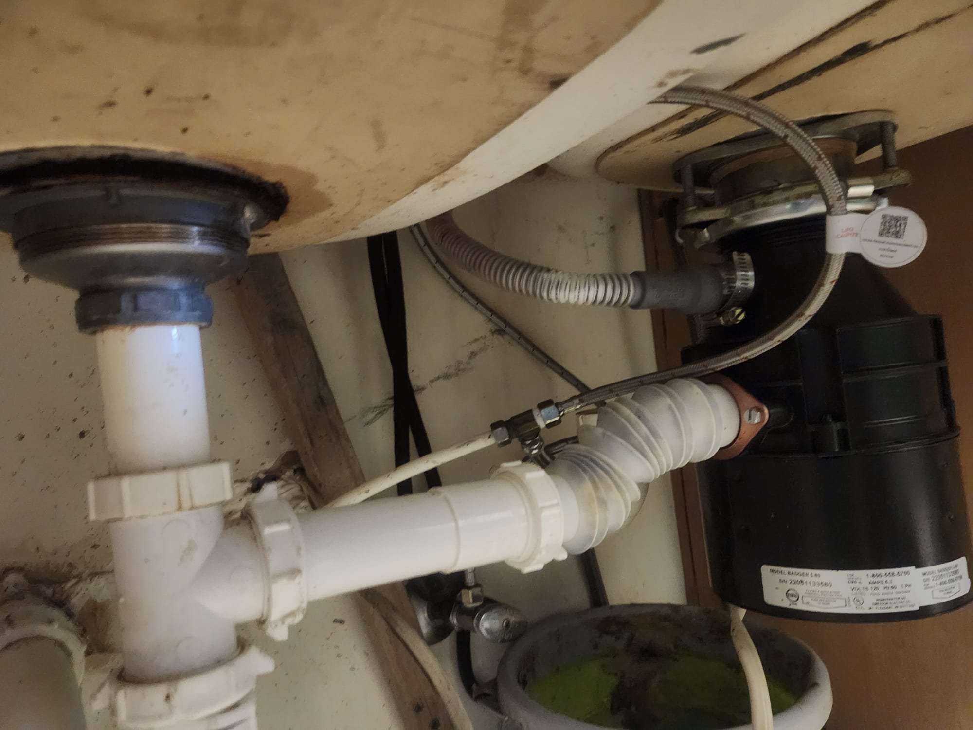 Under-sink plumbing with a bucket catching water during a leak check