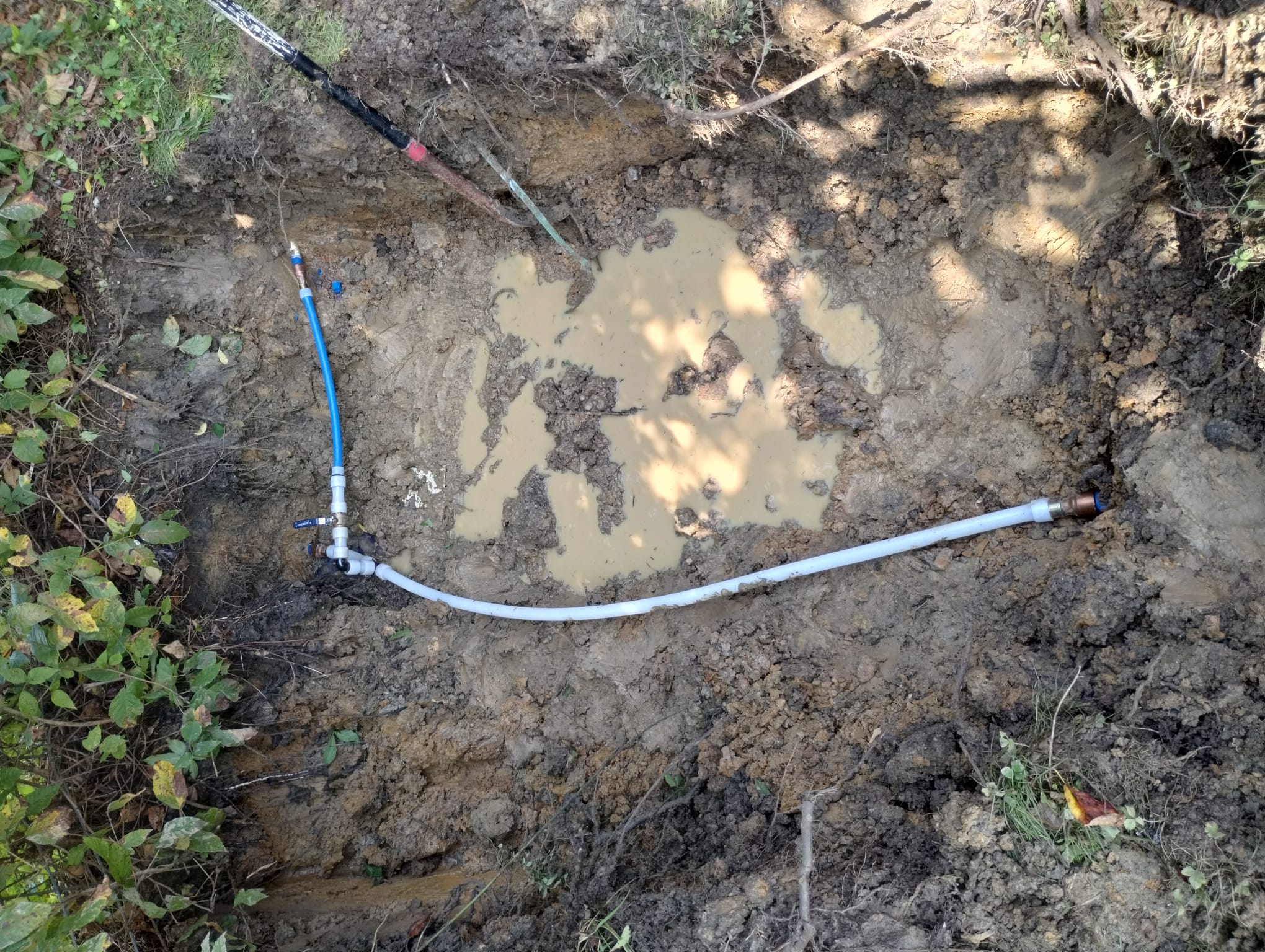 An open trench showing newly installed pipe and fittings during plumbing repair